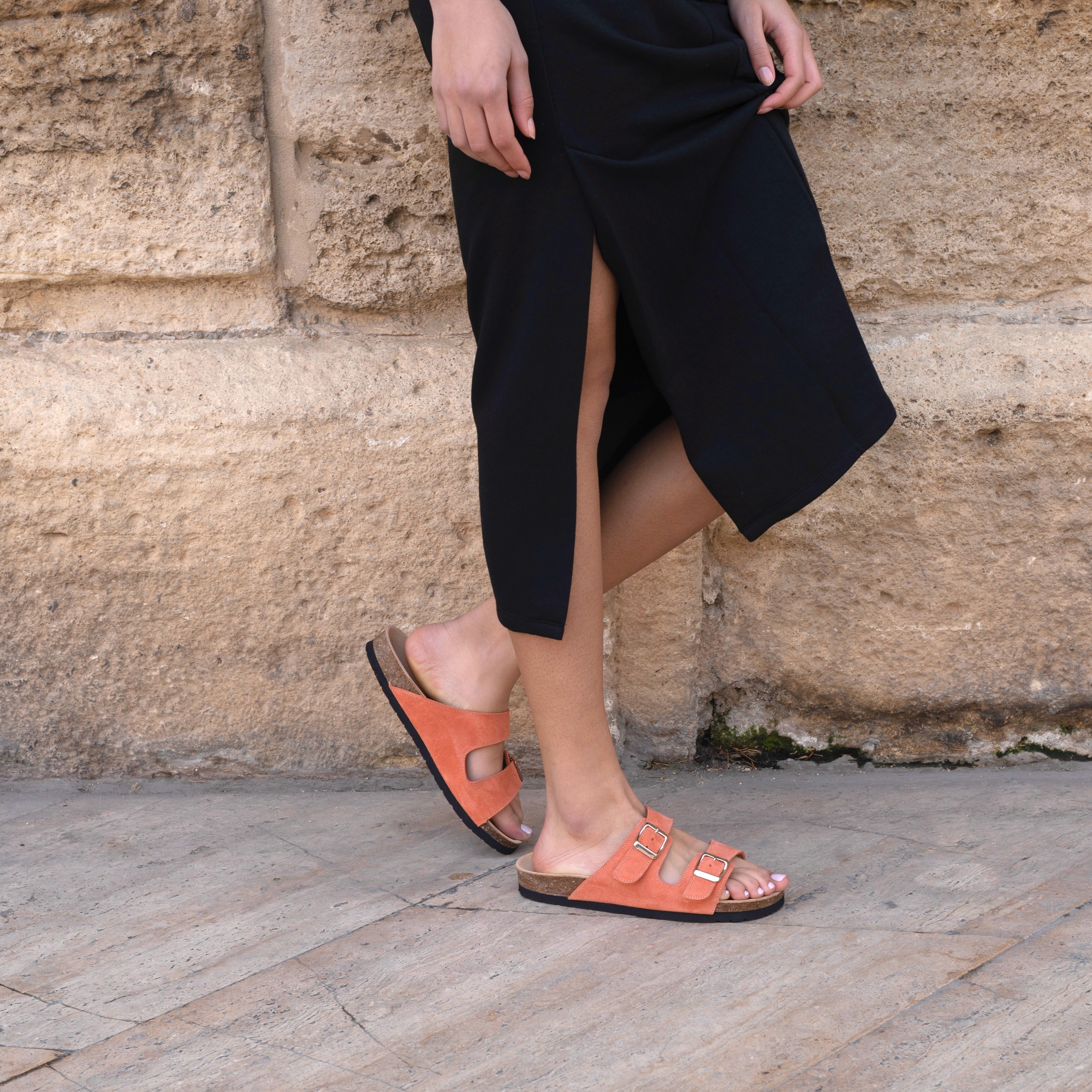 Zoon on woman wearing a midi black skirt and orange nordic sandals
