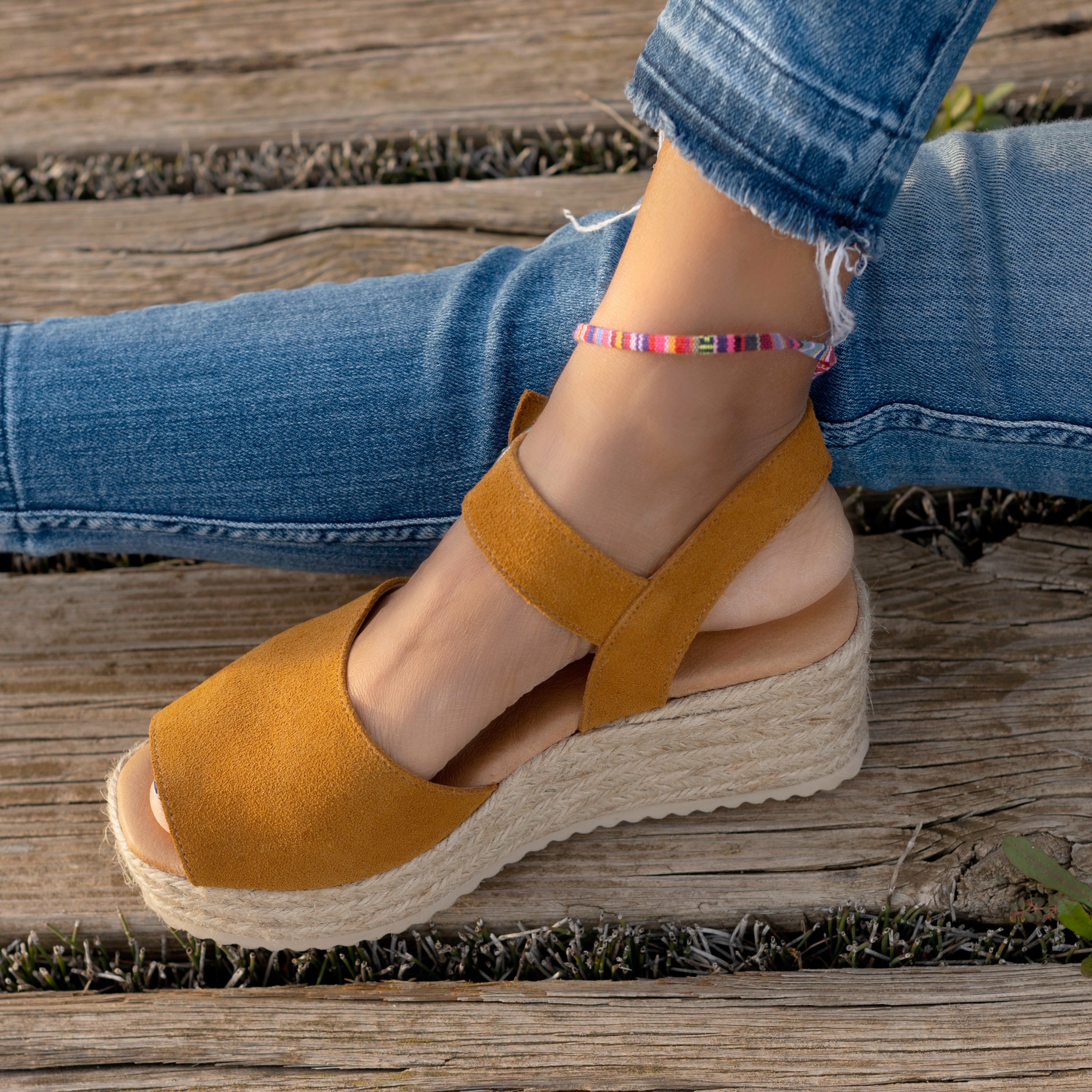 zoom on womans feet wearing platform sandals in whiskey and jeans