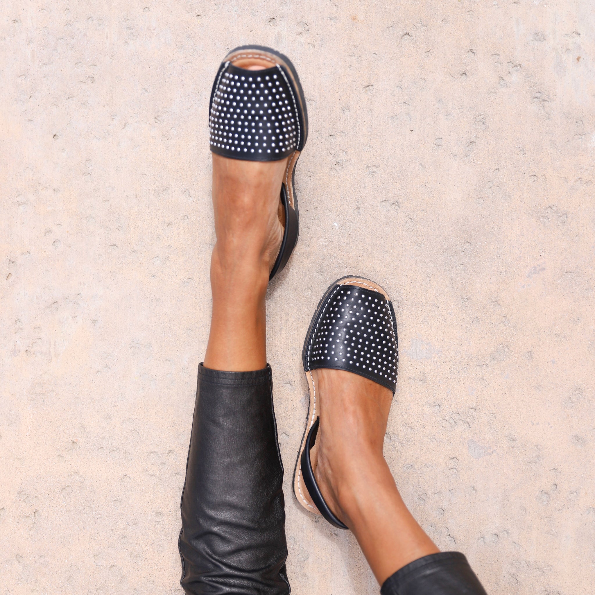 close up of woman's leg wearing black pants and black studded sandals 